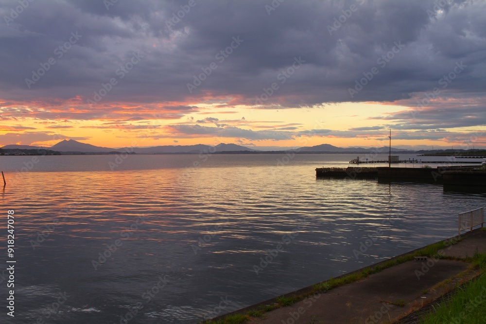 sunset on a lake pier with sky and water turning orange sunset on a lake pier with sky and water turning orange