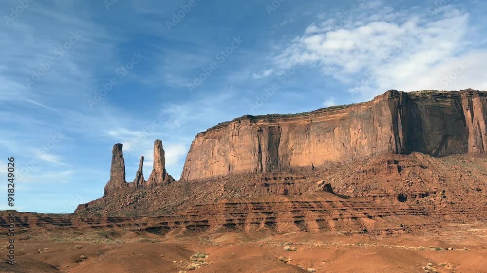 The Three Sisters rock formations at Monument Valley, Arizona on a bright sunny day with blue skies and white fluffy clouds. A large mesa is nearby in this scenic American Southwest Landscape - uSA The Three Sisters rock formations at Monument Valley, Arizona on a bright sunny day with blue skies and white fluffy clouds. A large mesa is nearby in this scenic American Southwest Landscape - uSA
