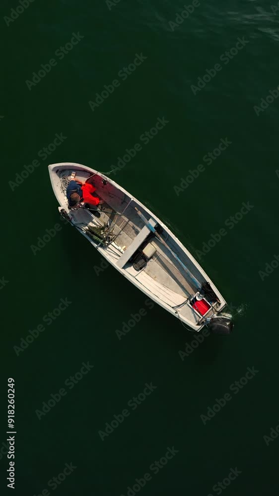 Vertical and zenithal aerial shot with the drone of a little fishing boat on the lake. Vertical and zenithal aerial shot with the drone of a little fishing boat on the lake.