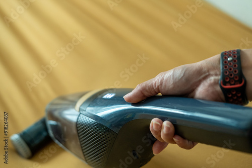 Asian woman's hands using vacuum cleaner on sofa