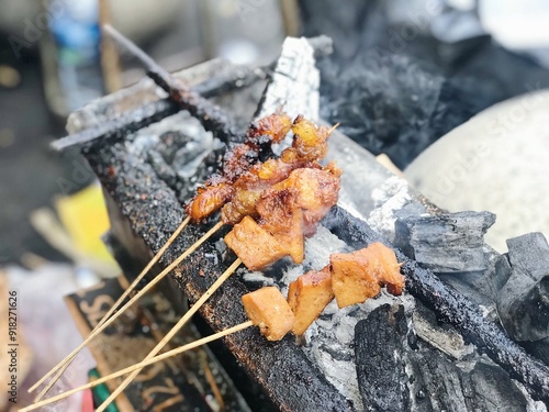 Yogyakarta, Indonesia - January 2019: Cheap satay grilled on smoke charcoal found at traditional market photo