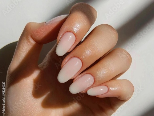 Elegant hand with stylish gradient manicure showcasing soft pastel nail color in subtle lighting.