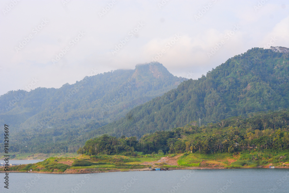 A tranquil landscape with a lake among the clouds. A mountain river flows from forested hills to a glacial lake. Snowy mountains in the mist. A small river and coniferous trees are reflected in a calm A tranquil landscape with a lake among the clouds. A mountain river flows from forested hills to a glacial lake. Snowy mountains in the mist. A small river and coniferous trees are reflected in a calm