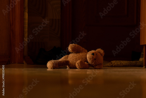 Brown soft teddy bear lies on the floor in the hallway in the apartment abandoned by itself