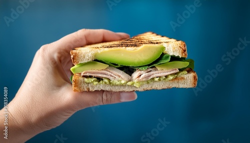 Hand holding a healthy panini of turkey and avocado
