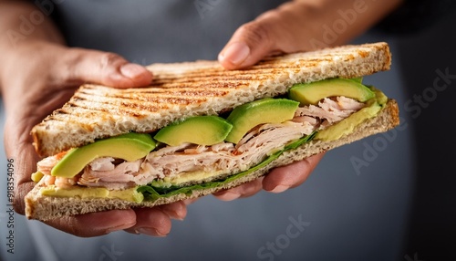 Hand holding a healthy panini of turkey and avocado