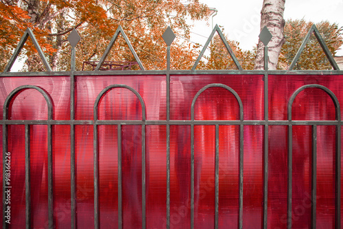 A fragment of a fence made of steel pipes and polycarbonate to protect private property, a summer day photo