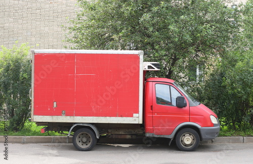 A small red refrigerated truck is parked near the lawn, Iskrovsky Prospekt, St. Petersburg, Russia, August 11, 2024 photo