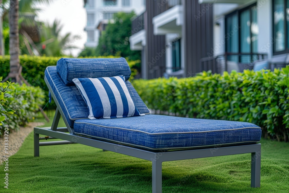 Blue and white outdoor sunbed with striped pillow on the lawn of a Thailand apartment complex, photographed in a professional style. Blue and white outdoor sunbed with striped pillow on the lawn of a Thailand apartment complex, photographed in a professional style.