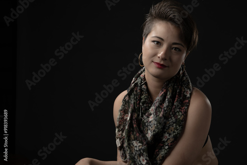 A young woman wearing a black top accentuated by a floral scarf draped over her shoulders, against a dark background, evoking a sense of calm and modern style.
