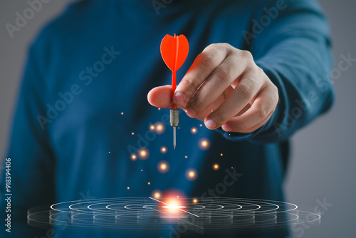 Obraz na plátně Person holding red dart aiming at target, symbolizing focus, precision, and achievement in achieving goals