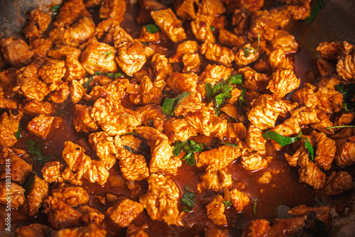 The turkey, cut into small pieces, is fried in a pan in tomato sauce with parsley.