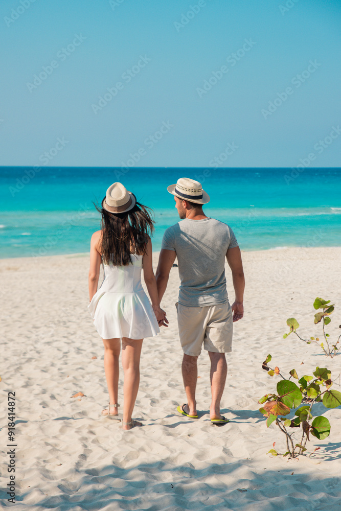 Pareja de jovenes apuestos entrando a una playa paradisiaca en verano con un sol radiante y un mar azul. Pareja de jovenes apuestos entrando a una playa paradisiaca en verano con un sol radiante y un mar azul.