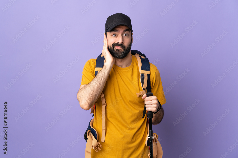 Caucasian handsome man with backpack and trekking poles over isolated background frustrated and covering ears Caucasian handsome man with backpack and trekking poles over isolated background frustrated and covering ears