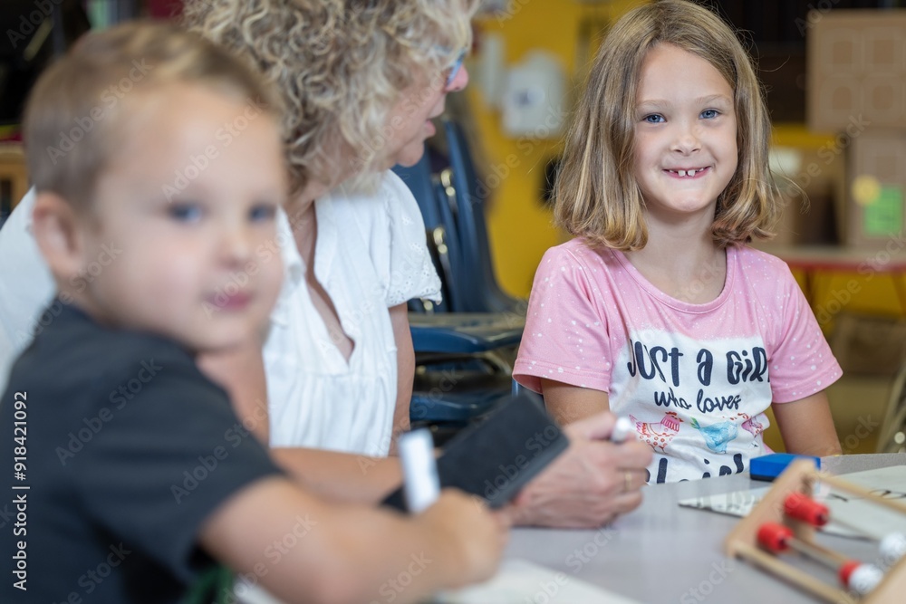 A teacher is helping a child with a math problem. The teacher is reviewing the students work in the classroom setting. A teacher is helping a child with a math problem. The teacher is reviewing the students work in the classroom setting.