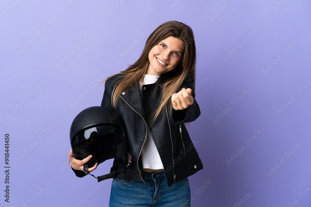 Young slovak woman holding a motorcycle helmet isolated on purple background making money gesture Young slovak woman holding a motorcycle helmet isolated on purple background making money gesture