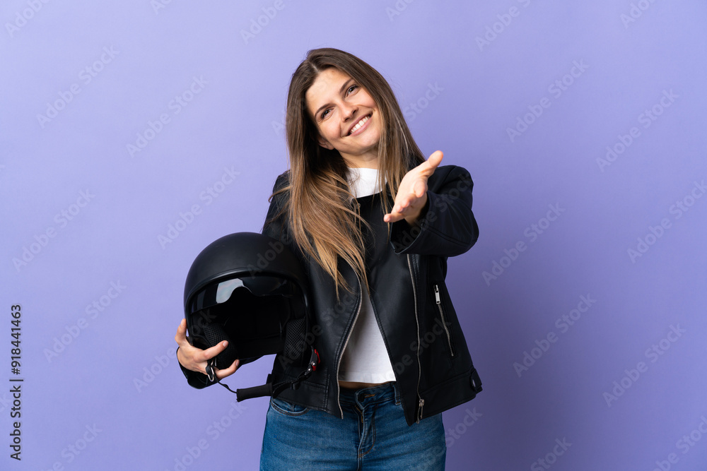 Young slovak woman holding a motorcycle helmet isolated on purple background shaking hands for closing a good deal Young slovak woman holding a motorcycle helmet isolated on purple background shaking hands for closing a good deal