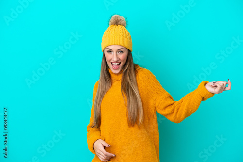 Young caucasian woman wearing winter jacket isolated on blue background making guitar gesture photo