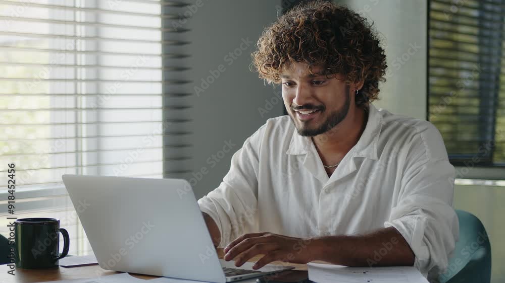 Happy businessman works on a laptop while sitting at workplace in home office. Happy businessman works on a laptop while sitting at workplace in home office.