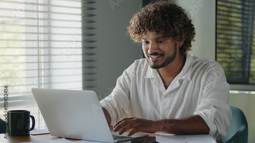 Happy businessman works on a laptop while sitting at workplace in home office. 
