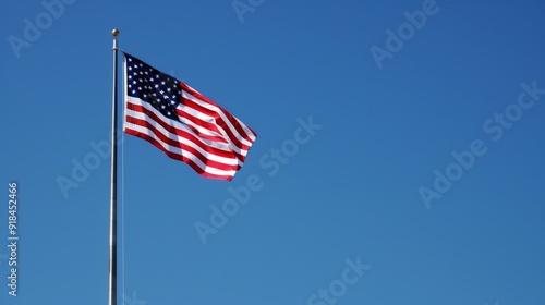 A patriotic shot of the American flag waving in the wind, with clear blue skies in the background