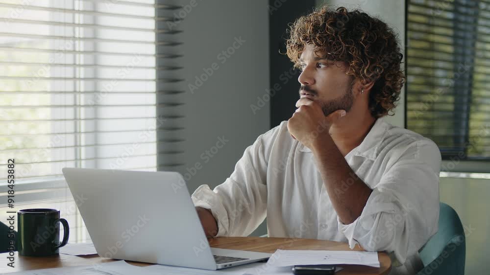Young Indian business man using computer, typing, working in home office, analyzing online data market, thinking, planning technology strategy. Young Indian business man using computer, typing, working in home office, analyzing online data market, thinking, planning technology strategy.