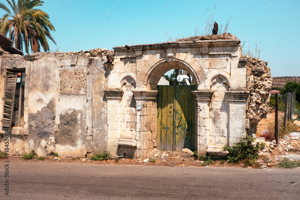 Fototapeta premium weathered ruins of a historical building with a green wooden door under the bright sun