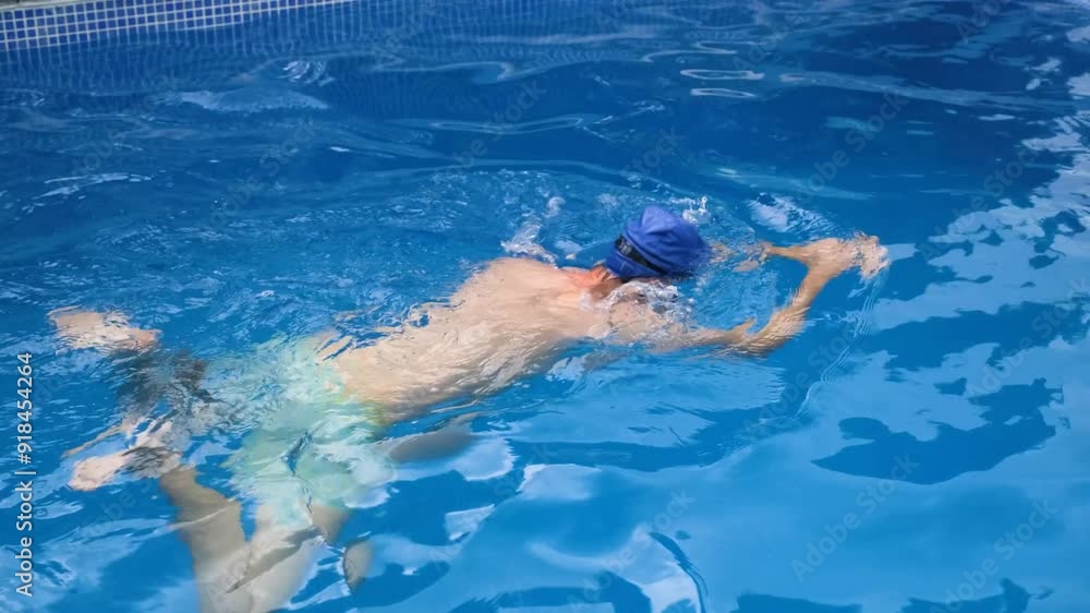 Man practices freestyle swimming in a clear pool, focusing on stroke technique and breathing for competitive training Man practices freestyle swimming in a clear pool, focusing on stroke technique and breathing for competitive training