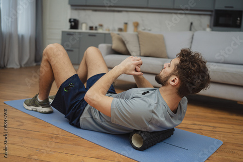 Beautiful young man in sports clothing exercising at home
