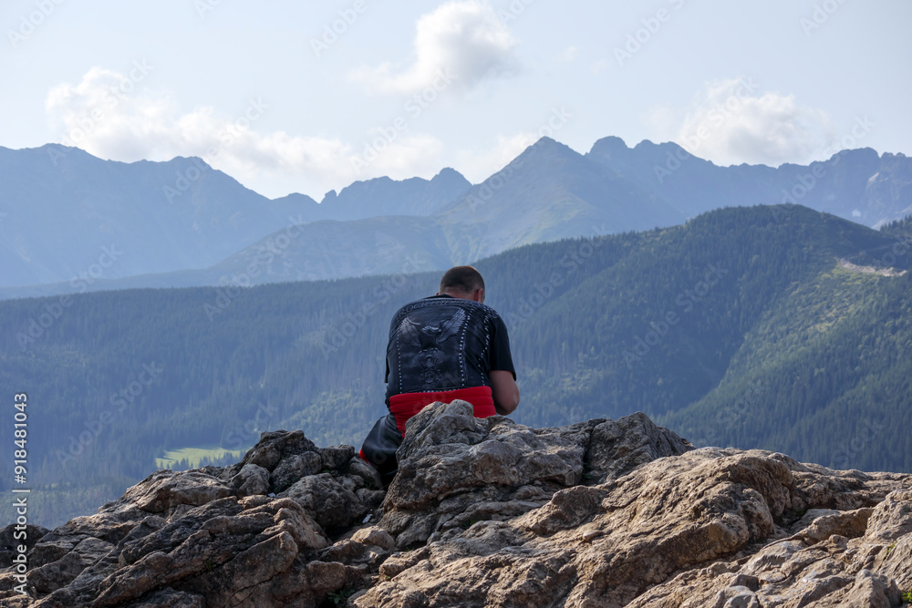 Fototapeta premium the traveler sits on the top of the mountain and looks over the mountains