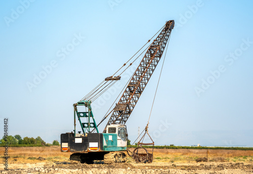 Telescopic crawler crane working to clean the canal.