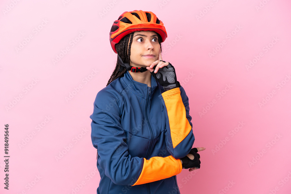 Teenager cyclist girl isolated on pink background having doubts and thinking Teenager cyclist girl isolated on pink background having doubts and thinking