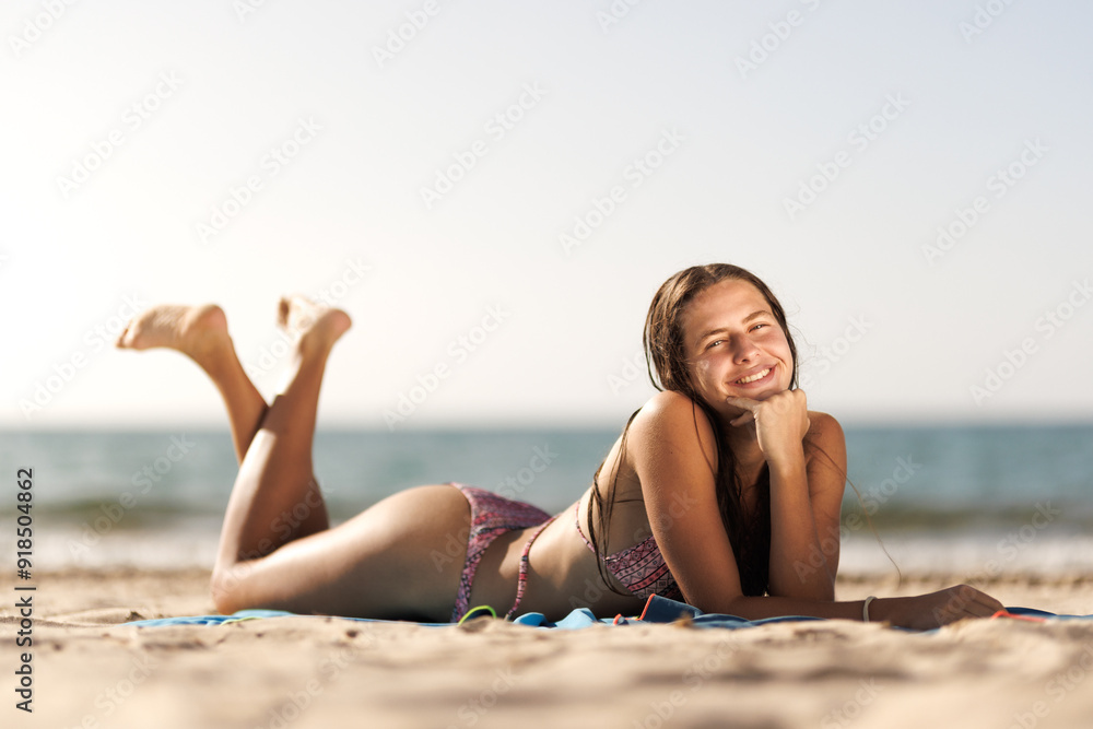 Smiling woman in bikini relaxing on a sandy beach on a sunny day by the ocean Smiling woman in bikini relaxing on a sandy beach on a sunny day by the ocean