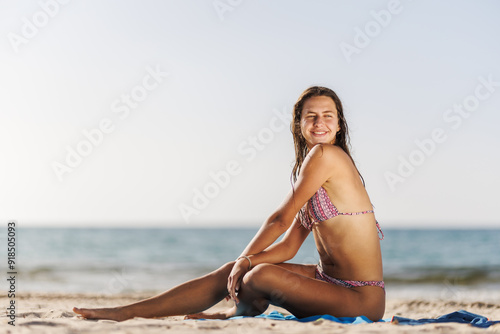 Young woman relaxing on the beach in a bikini enjoying a sunny day by the sea