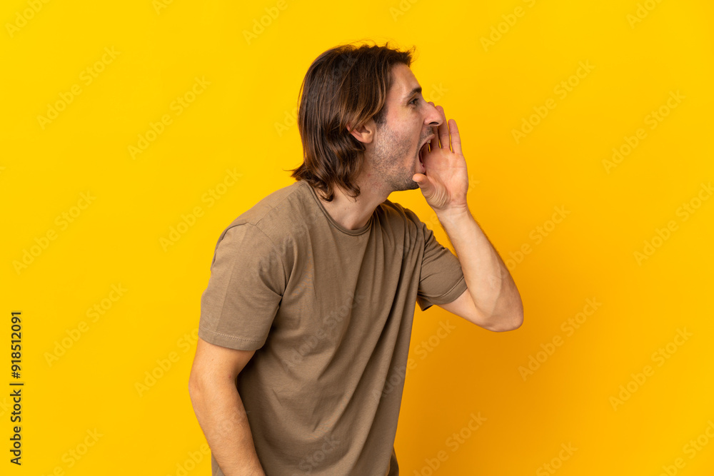Young handsome man isolated on yellow background shouting with mouth wide open to the side Young handsome man isolated on yellow background shouting with mouth wide open to the side