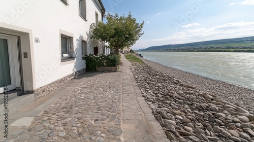 A picturesque castle sits gracefully on a rocky outcrop beside the Rhine, surrounded by lush greenery and mountains under a vibrant blue sky