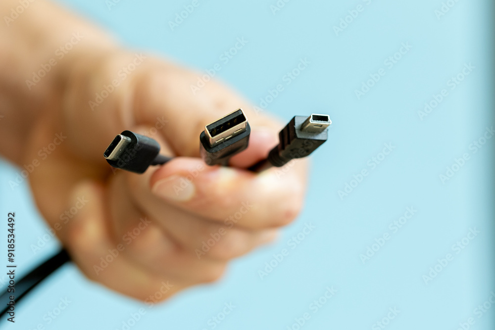 Fototapeta premium man holding several cables in hand, different types of USB cables, technology and connection concept
