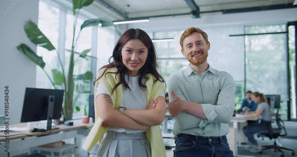 Two people standing side by side and confidently looking directly at camera. Woman with dark hair and yellow sweater over her shoulders positively smiling. Handsome man with red hair crossing his arms Two people standing side by side and confidently looking directly at camera. Woman with dark hair and yellow sweater over her shoulders positively smiling. Handsome man with red hair crossing his arms
