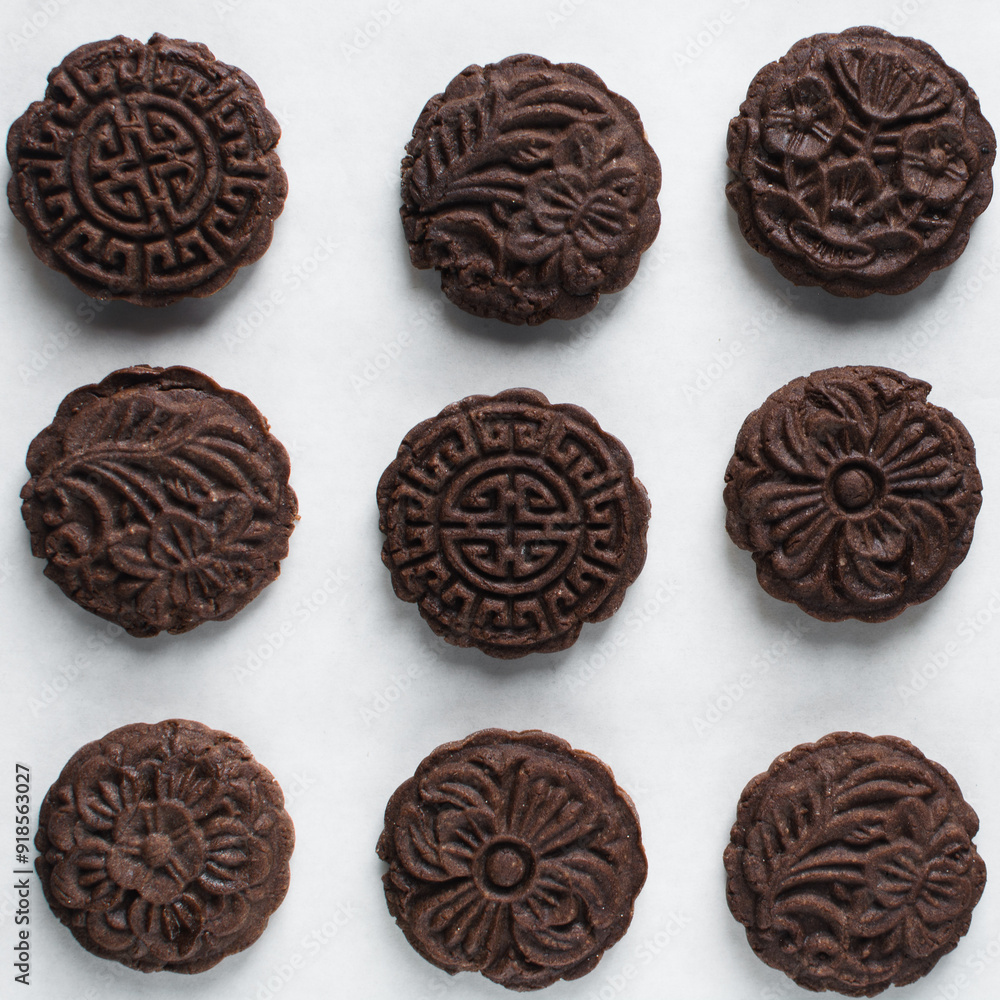 Overhead view of stamped chocolate cookies on a parchment lined baking tray, top view of embossed chocolate sugar cookies on a white background Overhead view of stamped chocolate cookies on a parchment lined baking tray, top view of embossed chocolate sugar cookies on a white background