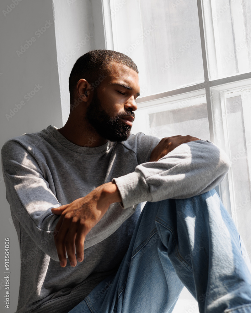 Relaxed african american man sitting in sunlight near window Relaxed african american man sitting in sunlight near window