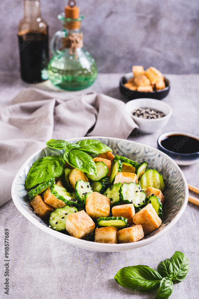 Fresh cucumber and fried tofu salad with basil leaves in bowl on table vertical view Fresh cucumber and fried tofu salad with basil leaves in bowl on table vertical view