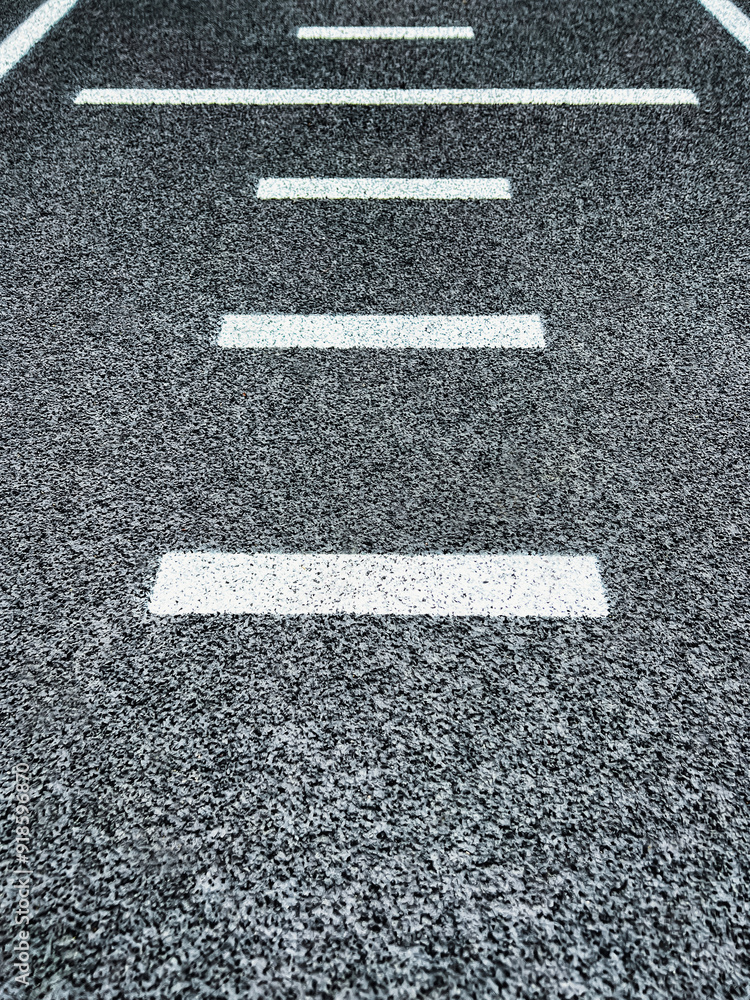 Fototapeta premium Textured black track or road surface with horizontal dashed lines. Artificial rubber black surface of a running track or road.