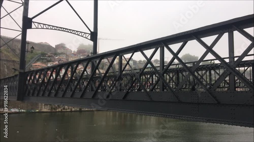 Lower deck of the Dom Luis Bridge in the city of Porto located in Portugal, with a morning foggy day, a car and a ciclist passing by