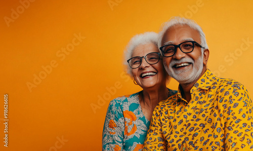 Crazy smiling indian senior couple, isolated orange color background, image with space for text
