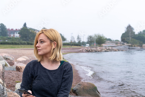 portrait of blonde woman on the beach in Eira Helsinki Finland enjoying the calmness of the sea