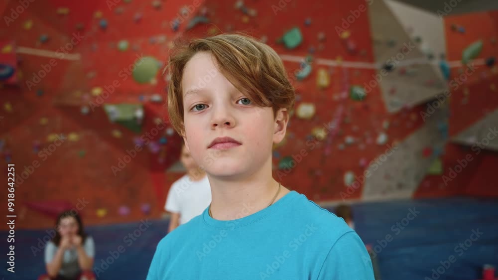 Portrait of a cute self-confident 10-year-old boy in a blue T-shirt, who stands in front of the camera against the wall of the indoor climbing wall. Strong, purposeful children in extreme sports. 4k Portrait of a cute self-confident 10-year-old boy in a blue T-shirt, who stands in front of the camera against the wall of the indoor climbing wall. Strong, purposeful children in extreme sports. 4k
