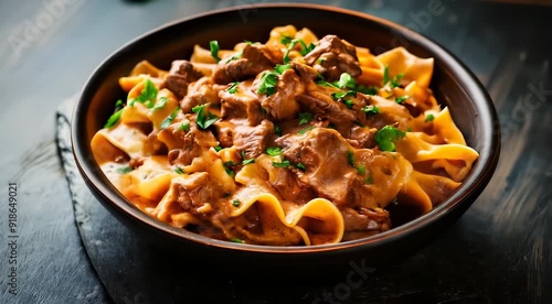 Traditional Hungarian food Beef Stroganoff. Tender beef cubes in creamy sauce over wide egg noodles, garnished with fresh parsley.
