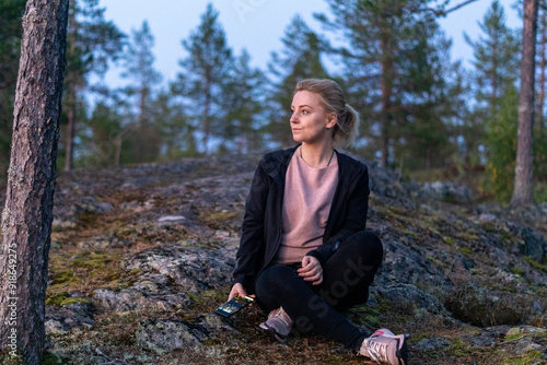 blonde woman hiking in the forest in Rovaniemi Finland Lapland, on a white night in summer with sunset