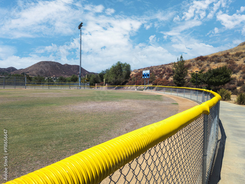 Wide angle shot of baseball outfield fence with yellow fence crown for safety