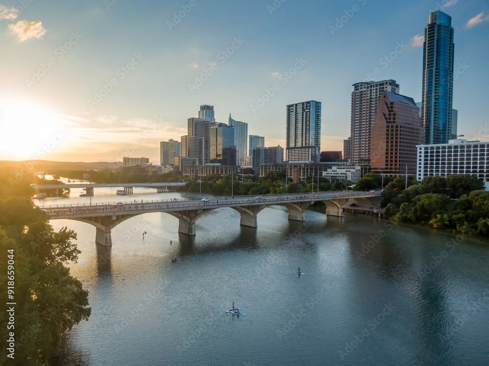 Naklejka premium The South Congress Bridge crossing the Colorado River into downtown Austin. Poeple are paddleboarding in the river Texas, United States.
